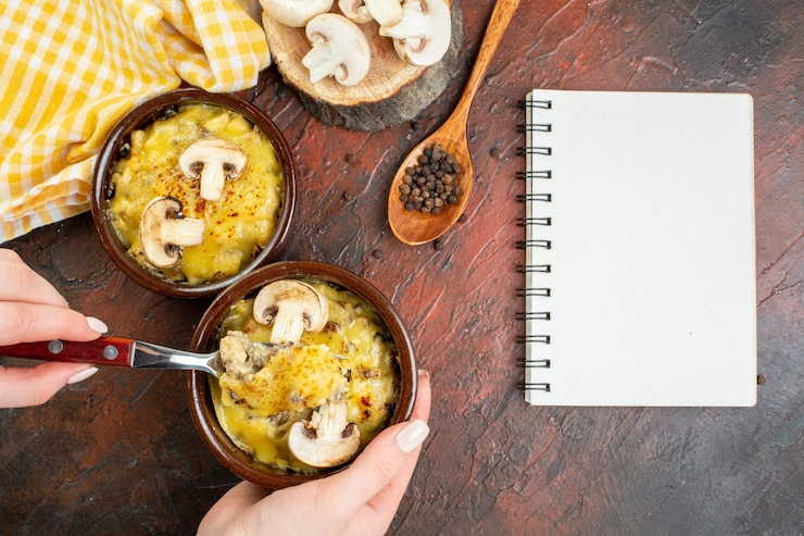 Photo gratuit champignon vue de dessus avec mosarella dans des bols fourchette dans une cuillère en bois de bloc-notes à main féminine sur une table rouge foncé