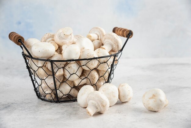 Champignons blancs dans un plateau métallique sur table en marbre.