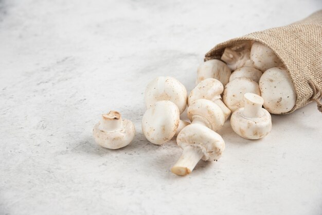 Champignons blancs à l'intérieur de paniers rustiques sur table en marbre.