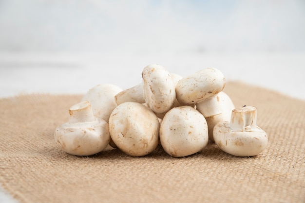 Champignons blancs isolés sur un morceau de toile de jute.