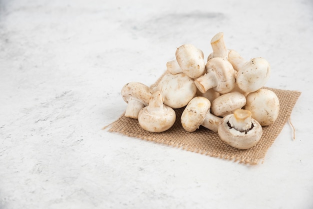 Champignons blancs isolés sur un morceau de toile de jute.