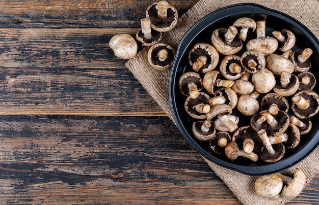 Champignons blancs sur sac en tissu sur une table en bois foncé. mise à plat.