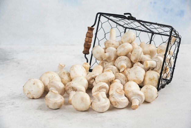 Champignons blancs sortis d'un panier métallique.