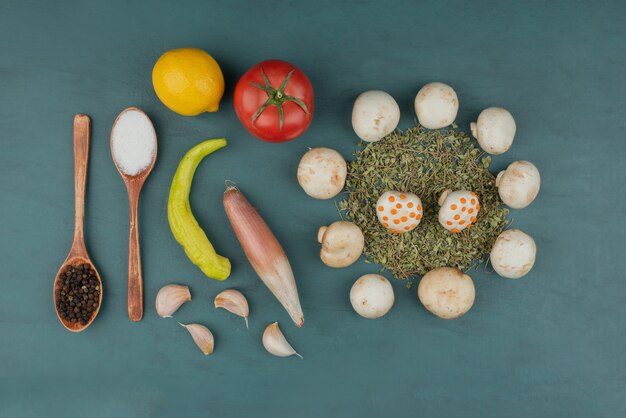 Champignons, citron, poivre, menthe, tomate et épices sur table bleue.
