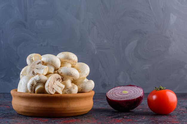 Champignons frais avec tomate rouge et oignon violet sur une surface sombre