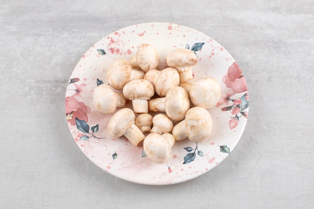 Champignons mûrs sur une assiette, sur la table en marbre.