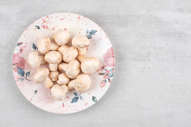 Champignons mûrs sur une assiette, sur la table en marbre.