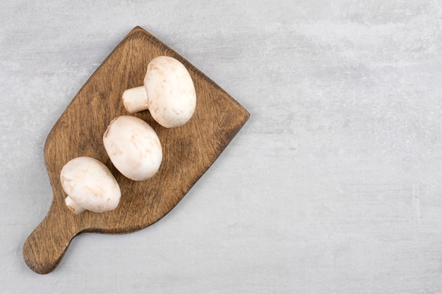 Champignons sur une planche à découper, sur la table en marbre.