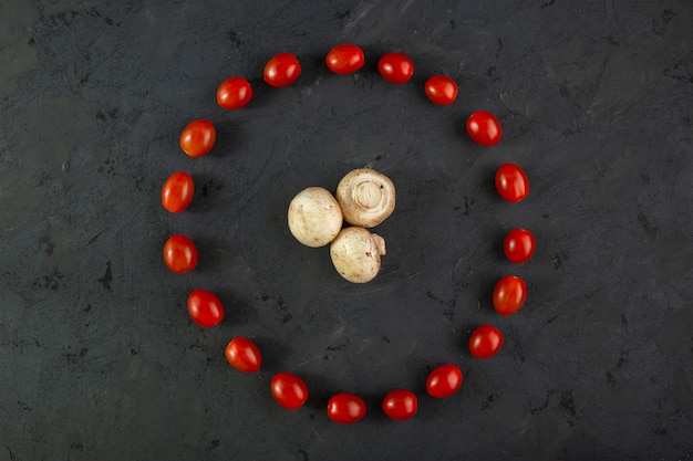 Champignons et tomates champignons mûrs avec tomates cerises moelleuses de forme ronde sur fond gris