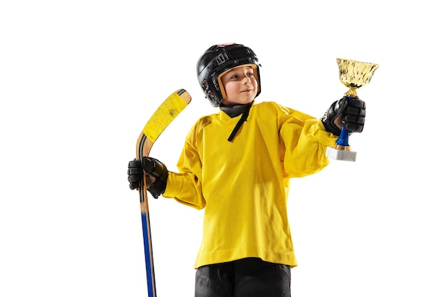 Champion. Petit joueur de hockey avec le bâton sur un court de glace et un mur blanc. Sportsboy portant équipement et formation de casque. Concept de sport, mode de vie sain, mouvement, mouvement, action.