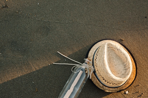 Chapeau et bouteille à la plage