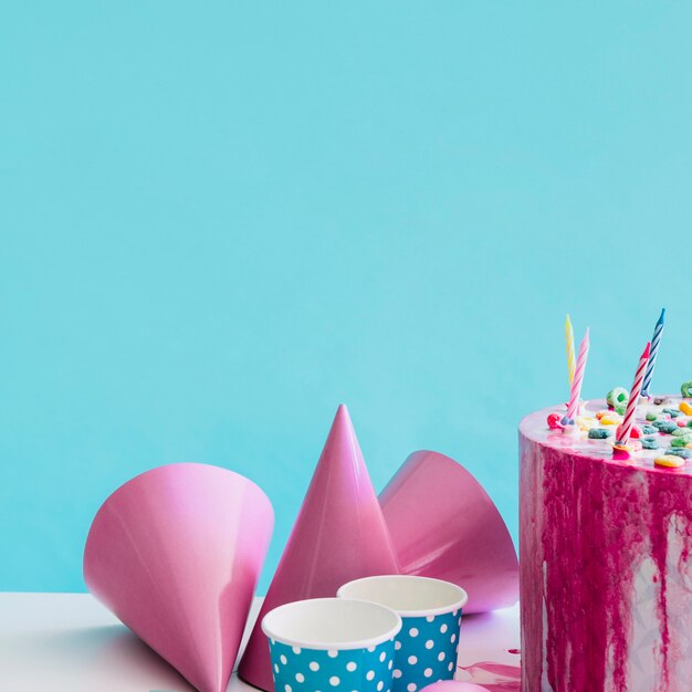 Chapeaux de fête et tasses près du gâteau