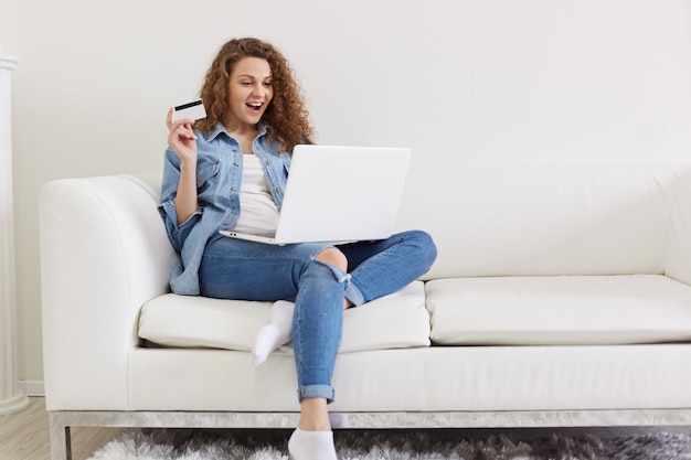 Charismatique séduisante femme aux cheveux bouclés ouvrant largement la bouche avec satisfaction