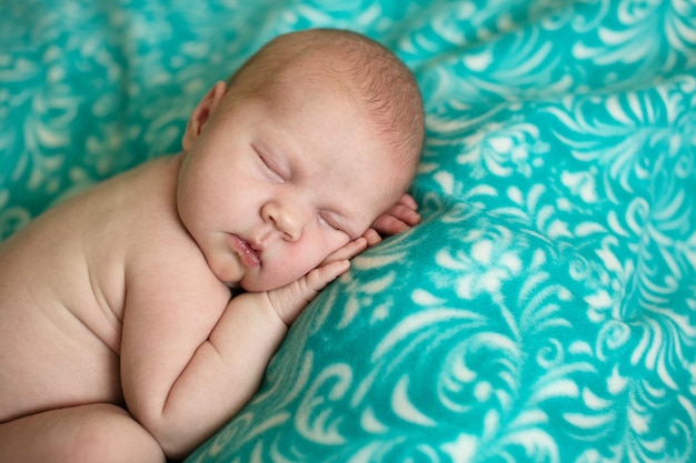 Charmant bébé dormant sur fond bleu vert