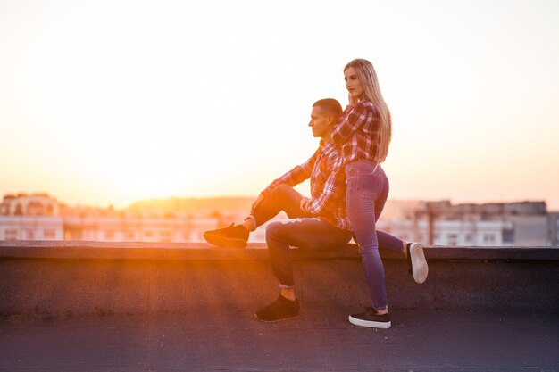 Le charmant couple amoureux assis sur le toit