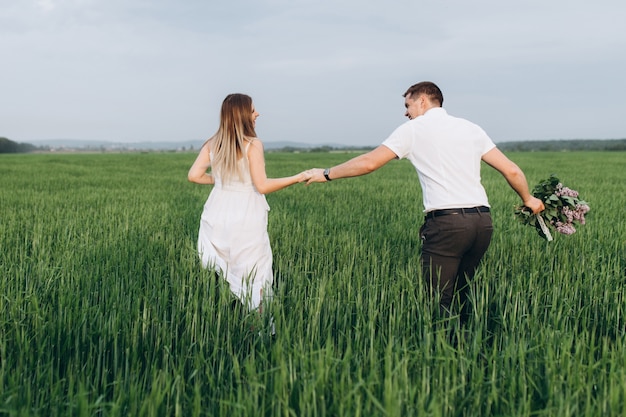 Le charmant couple amoureux marchant le long du champ