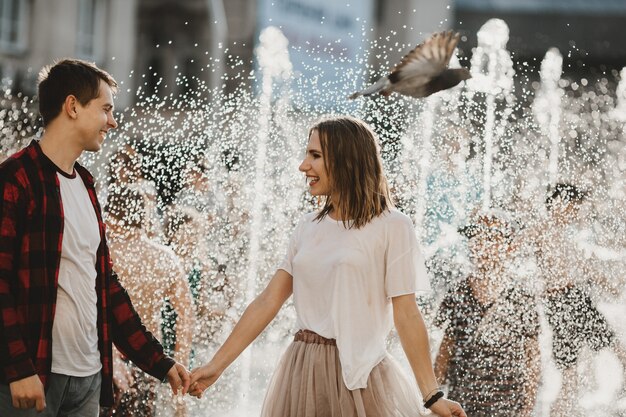 Le charmant couple amoureux marchant près de la fontaine