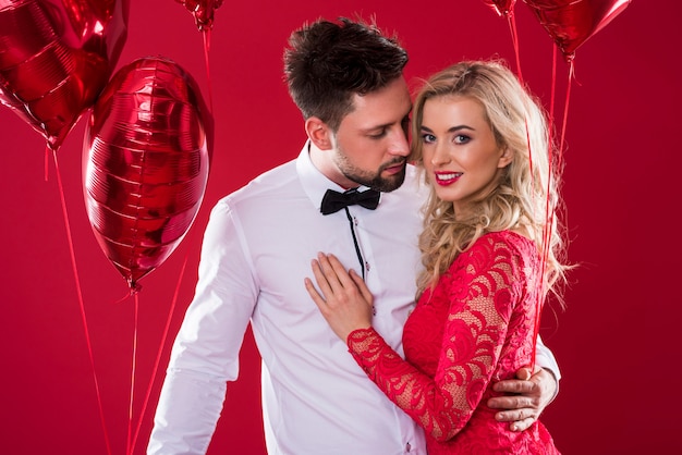 Charmant couple tenant deux bouquets de ballons rouges brillants