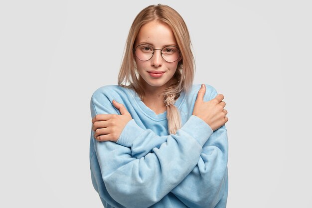 Charmante belle jeune femme de race blanche porte un pull bleu clair surdimensionné