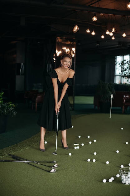 Charmante dame caucasienne pose pour la caméra et joue au golf, image isolée sur fond sombre flou