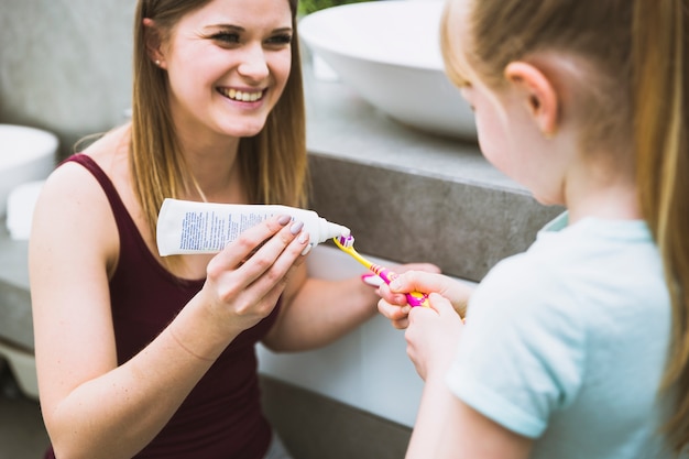 Charmante femme aidant sa fille avec du dentifrice