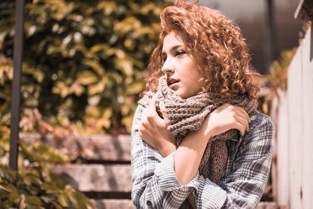 Charmante femme assise sur les marches avec les mains croisées