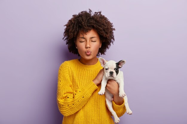 Charmante femme aux cheveux bouclés s'occupe d'un animal adorable