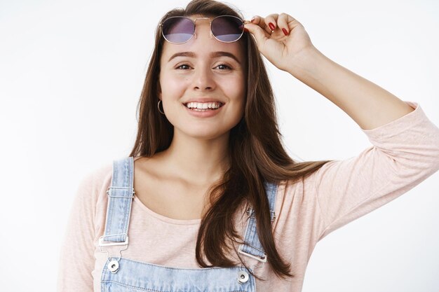 Charmante femme brune à l'allure amicale et insouciante enlevant des lunettes de soleil bleues à la recherche de rêve et d'espoir