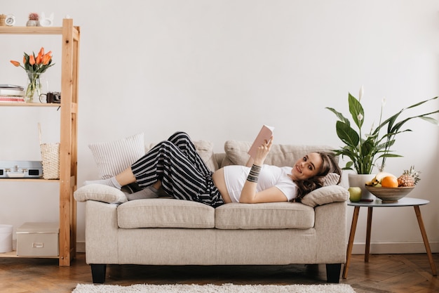 Charmante femme enceinte brune regarde à l'avant et sourit