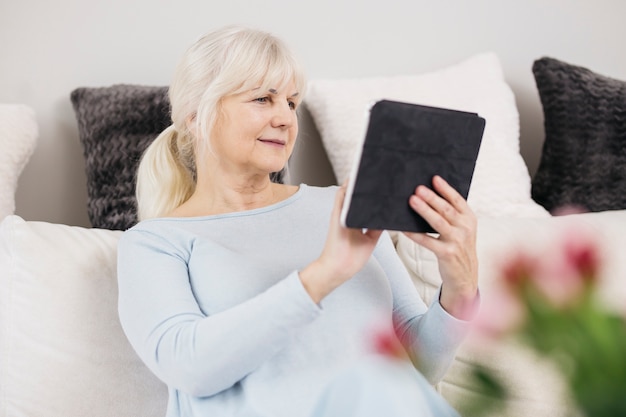 Photo gratuite charmante femme parcourant la tablette sur le canapé