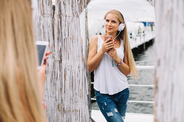 Charmante femme posant sur la plage avec des gadgets