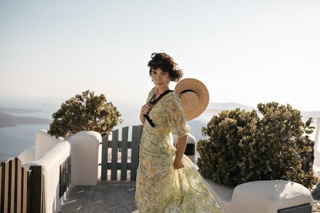 Charmante femme en robe à fleurs se penche sur l'appareil photo à l'extérieur