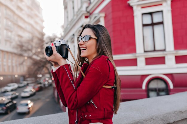 Charmante fille aux longs cheveux raides prenant une photo de la ville