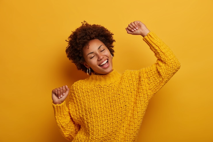 Photo gratuit une charmante fille à la peau sombre et animée danse joyeusement et célèbre la bonne nouvelle, se sent chanceuse et réussie