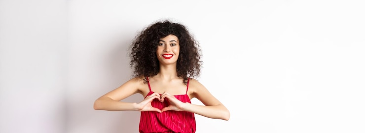 Photo gratuit charmante jeune femme avec des fraises romantiques rouges montrant un geste du cœur et un amour express souriant debout