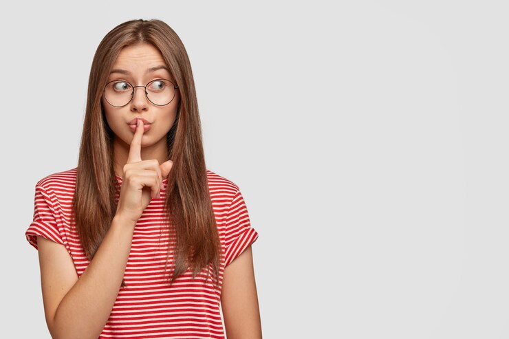 Photo gratuit charmante jeune femme inexpérimentée tente de cacher l'erreur du patron, garde l'index sur la bouche