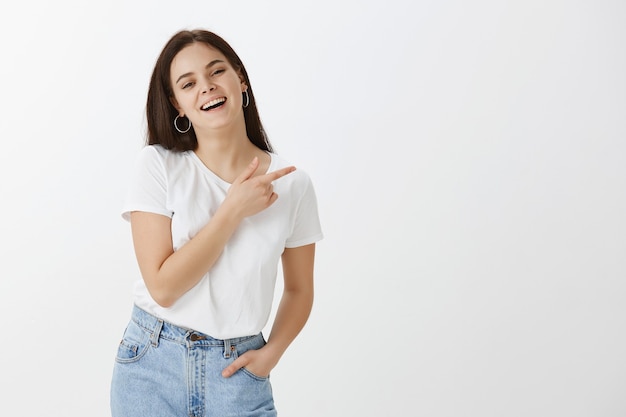 Charmante jeune femme posant contre le mur blanc