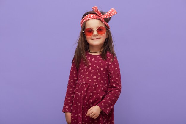 Charmante petite fille à la mode hipster habillée en robe bordeaux