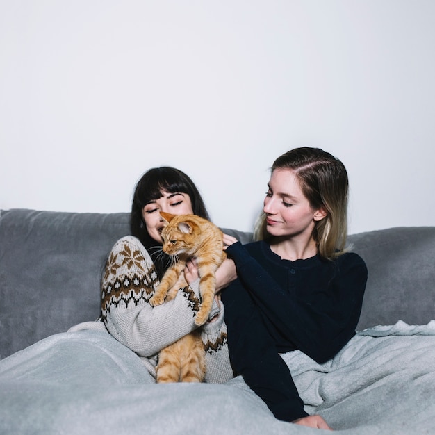 Charmantes filles câlins avec un chat sur le canapé