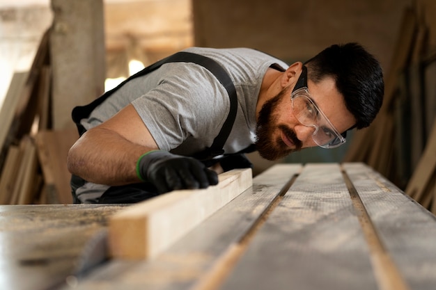 Photo gratuite charpentier coupant le panneau de forces de défense principale à l'intérieur de l'atelier