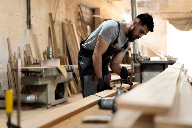 Charpentier coupant le panneau de forces de défense principale à l'intérieur de l'atelier