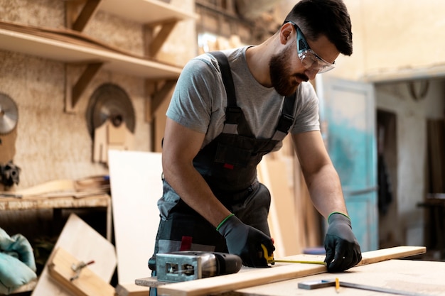 Photo gratuite charpentier coupant le panneau de forces de défense principale à l'intérieur de l'atelier