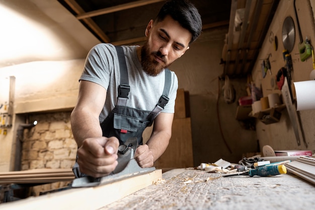 Charpentier coupant le panneau de forces de défense principale à l'intérieur de l'atelier