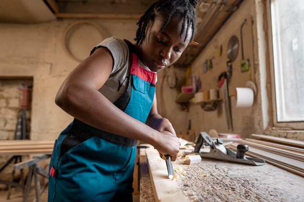 Charpentier coupant le panneau de forces de défense principale à l'intérieur de l'atelier