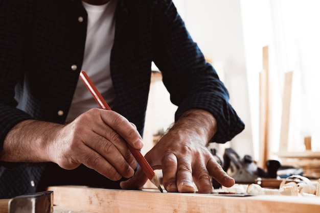 Le charpentier fait des marques de crayon sur une planche en bois