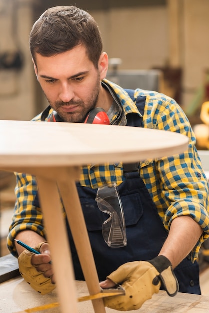 Photo gratuite un charpentier mesure la table en bois avec une règle