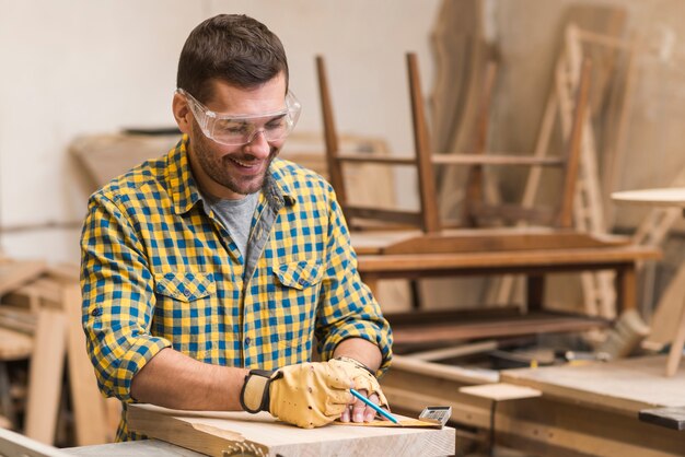 Charpentier professionnel souriant, mesurant le bloc de bois avec une règle