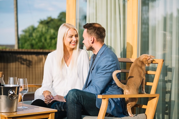 Chat brun près du couple romantique assis sur un banc dans le restaurant