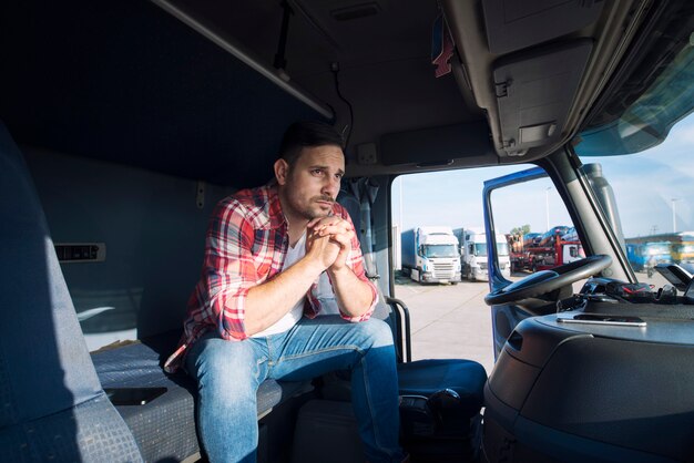 Chauffeur de camion assis dans sa cabine et pensant à sa famille