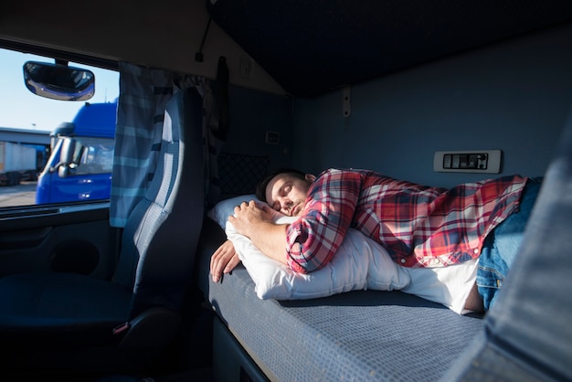 Chauffeur de camion dormant dans sa cabine après avoir effectué de longues heures supplémentaires